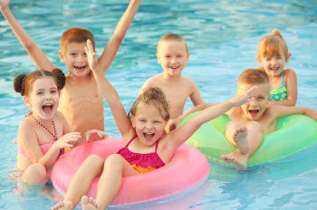 6 Kinder im Wasser 2 davon sind in Wassserringe drin und lachen in die Kamera