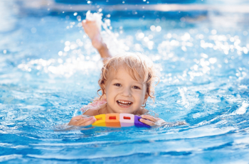 Ein Kind im Wasser welches schwimmt und lächelt